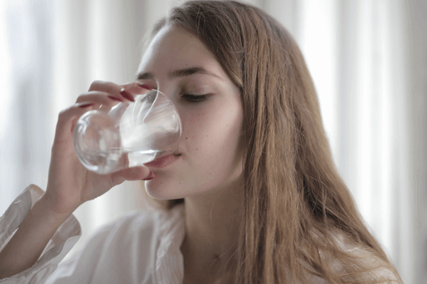 コップに入った水を飲む若い女性